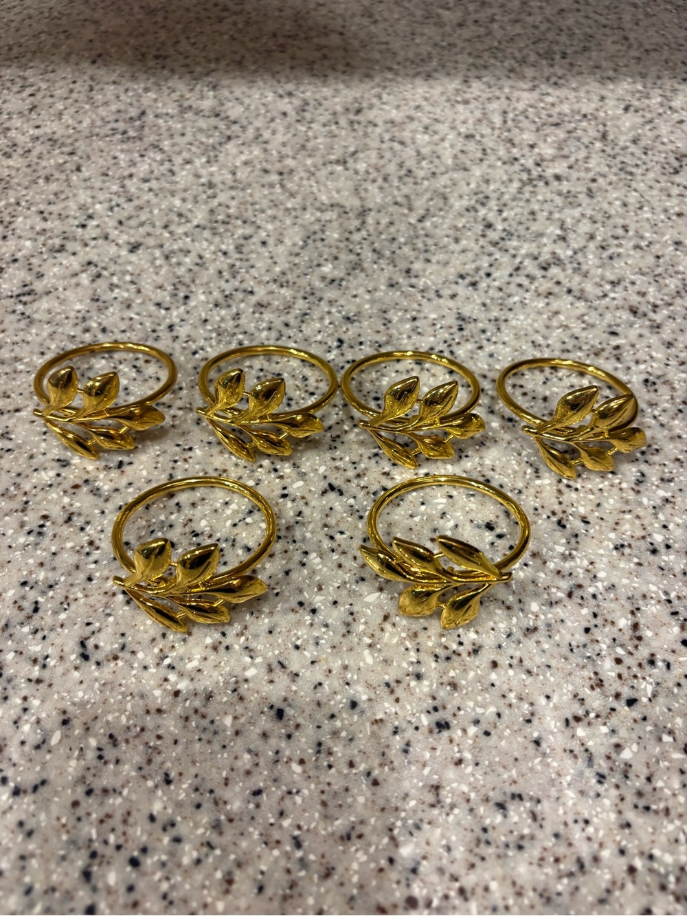 Gold metal napkin rings with a detailed leaf or olive branch design. Set Of 6